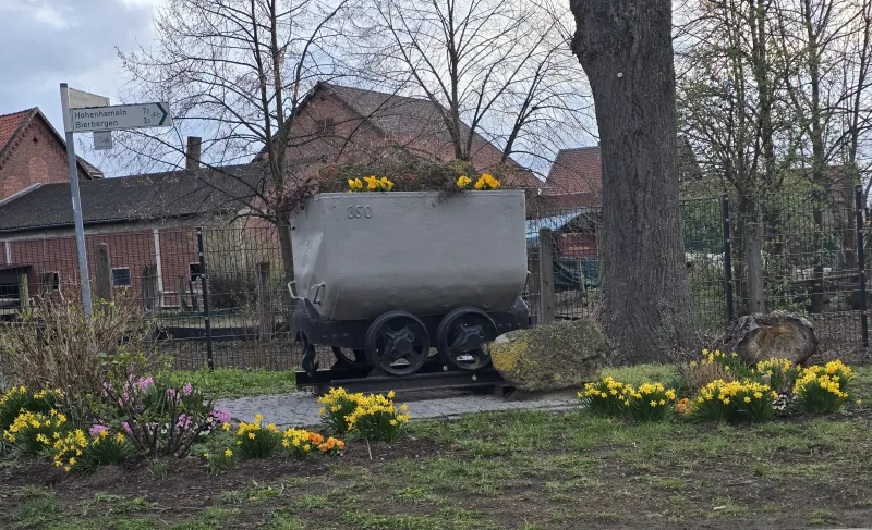 Frühlingshaft mit Narzissen bepflanzte Bergbaulore und ein Beet voller Osterglocken an der Großen Straße in Adenstedt